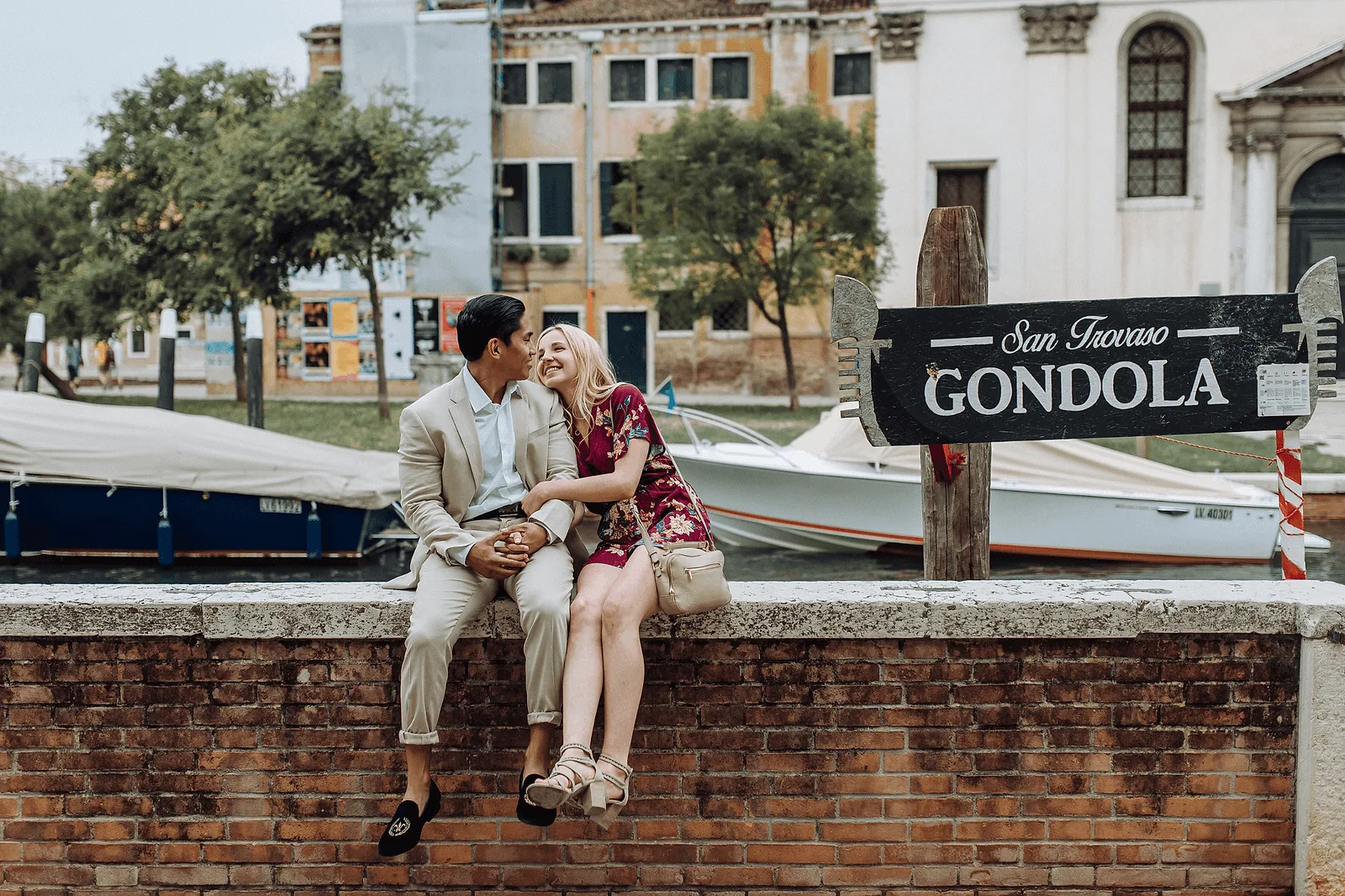 couple photoshoot in venice, europe: sitting on a fence with a boat view