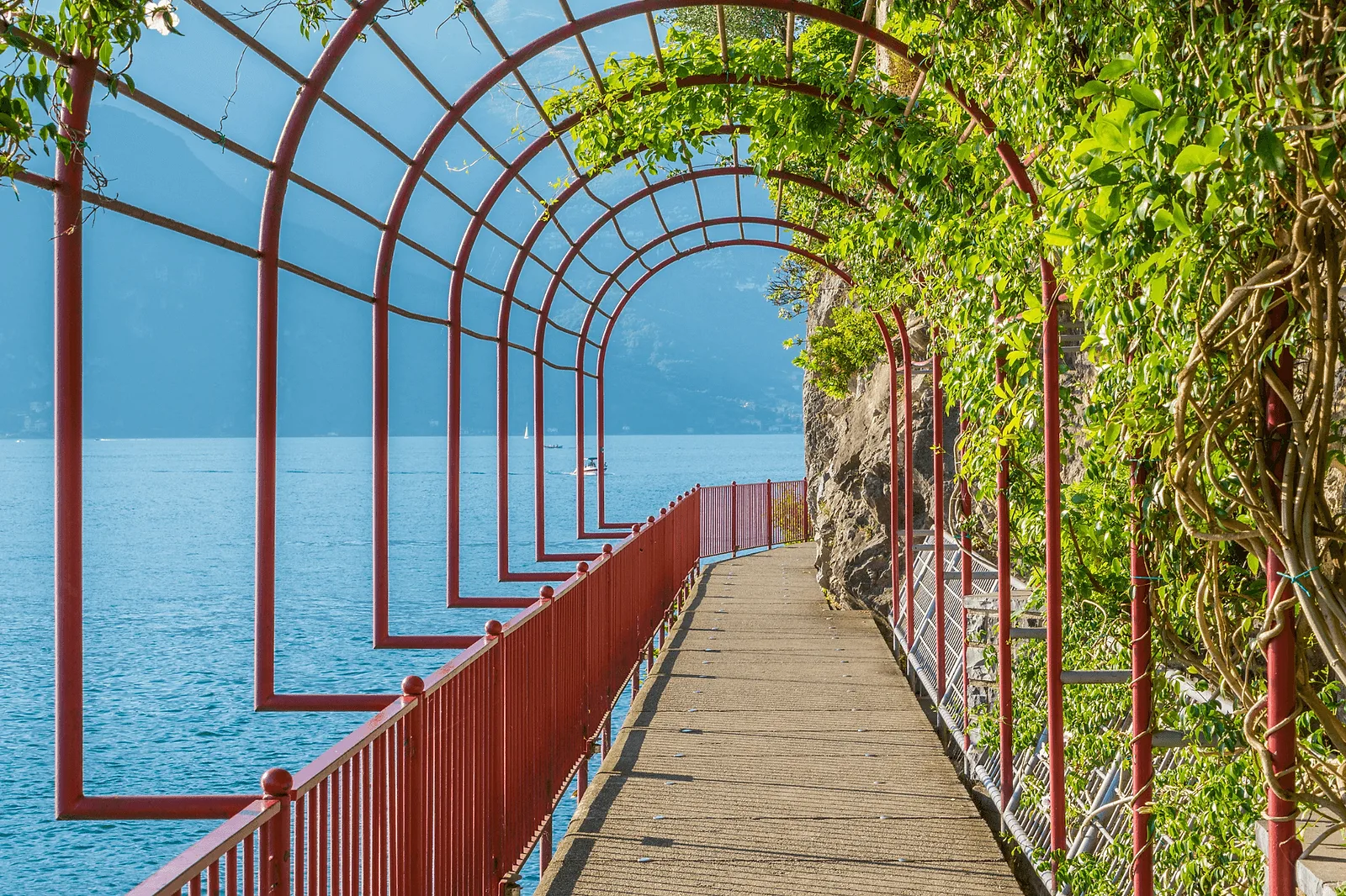 Varenna's Walk of Lovers Couple on the red-railed Passeggiata degli Innamorati cantilevered over the water in Varenna, Lake Como