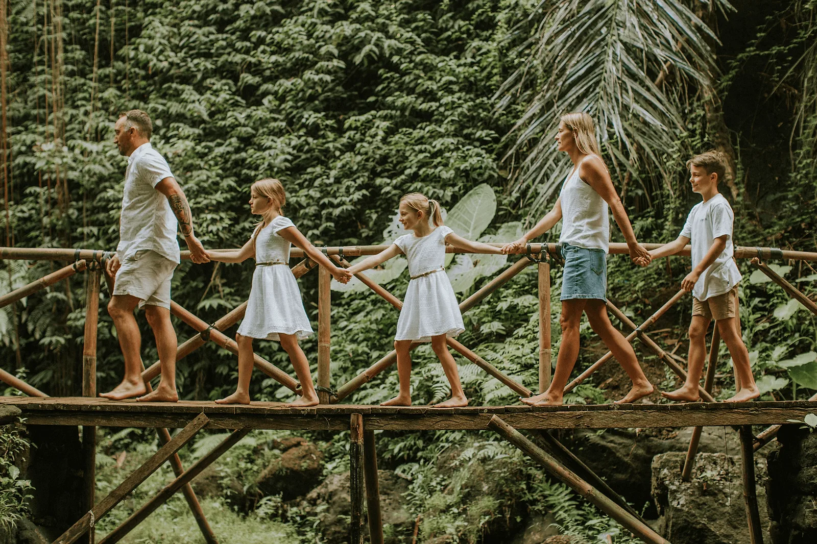 family in similar outfits walking on the bridge in bali