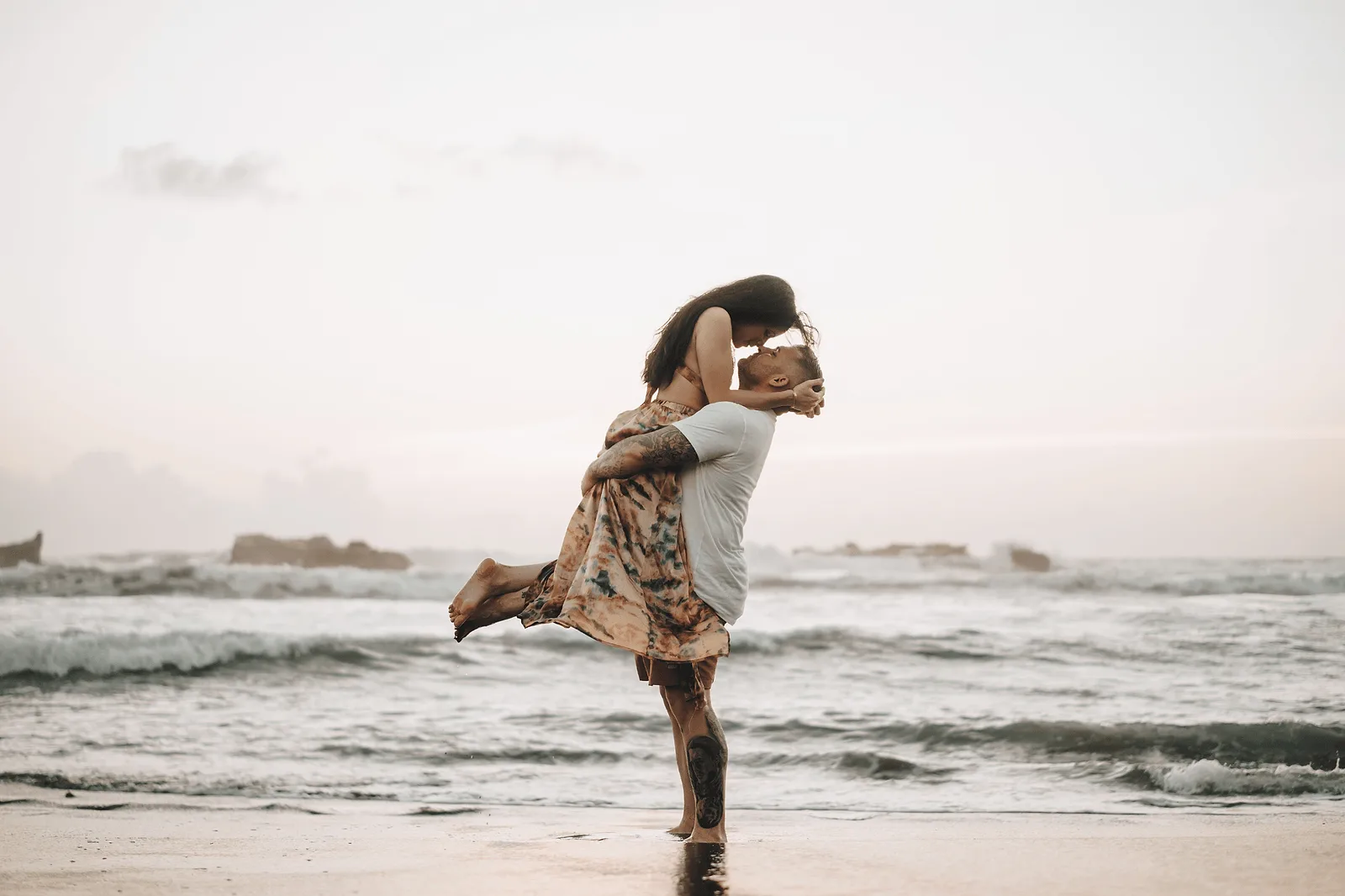 couple photoshoot in bali_ man holding a woman in his arms on the beach during golden hour