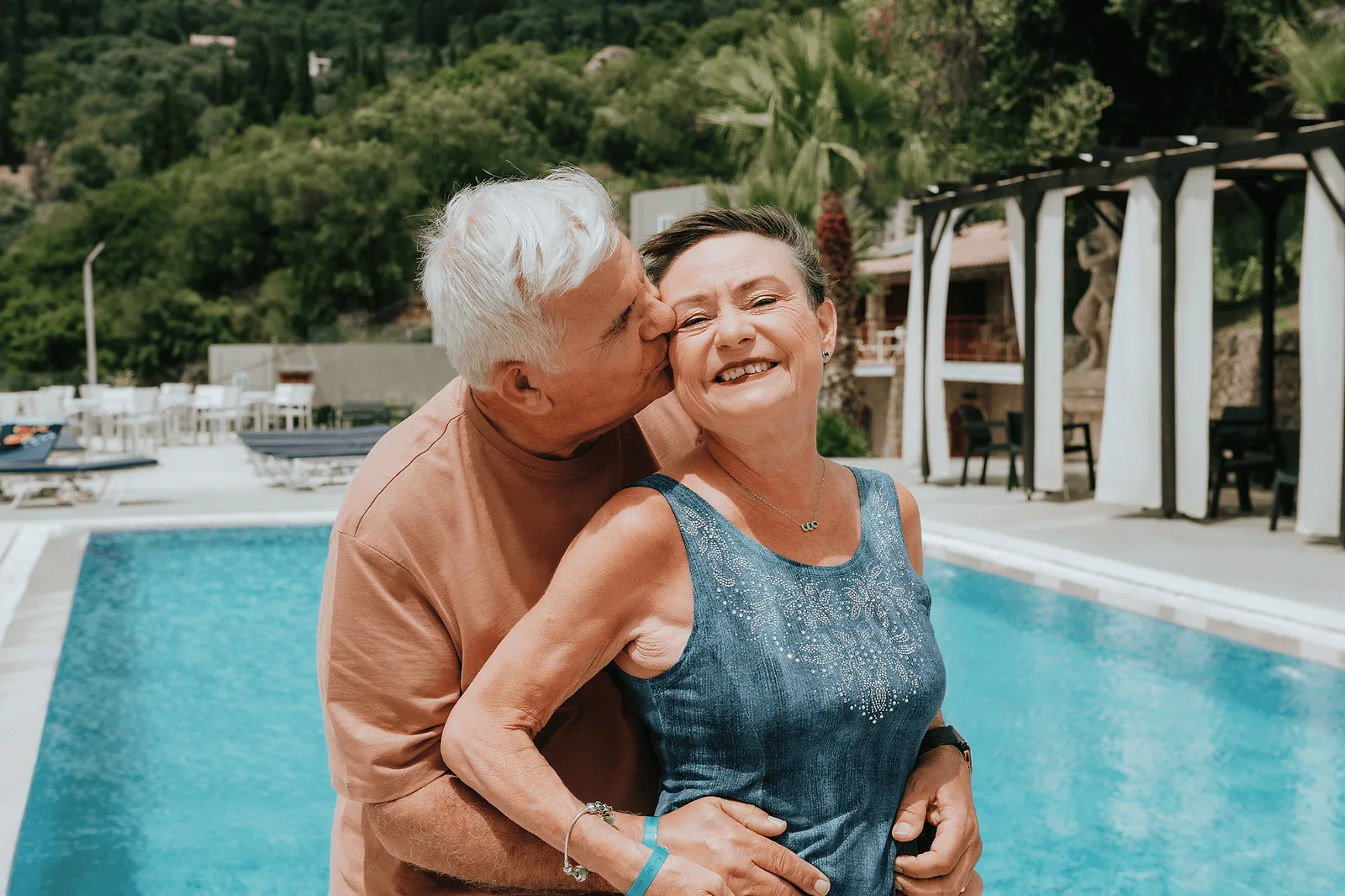 elderly couple in corfu standing in front of a pool