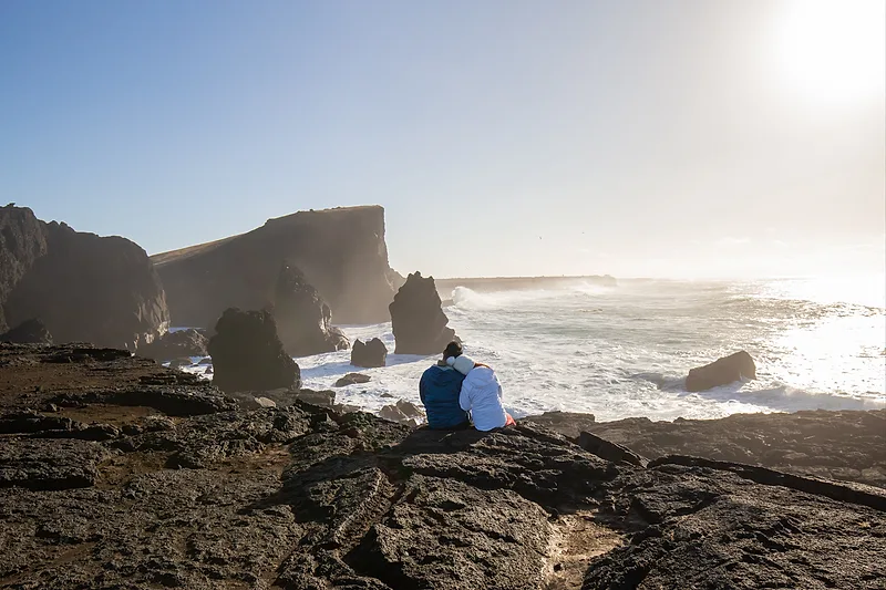 happy couple sitting on a coast in iceland