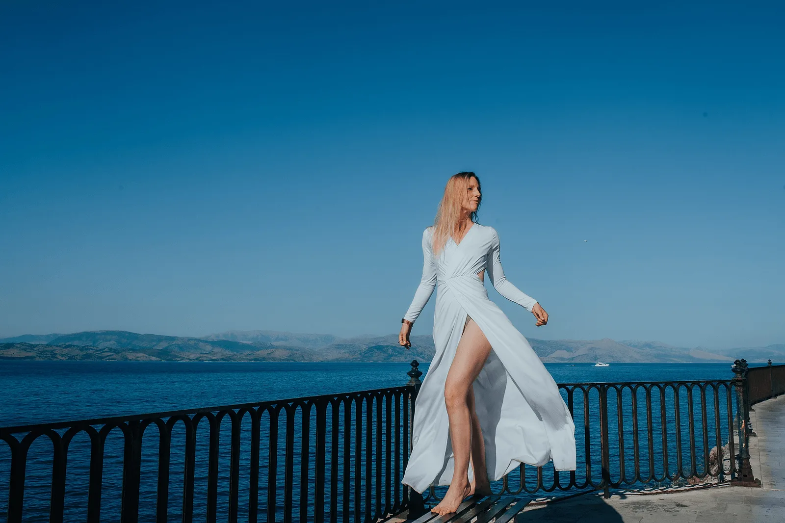 beautiful woman posing in the wind in white long dress on corfu, greece
