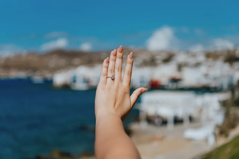 Engagement ring on woman's hand on Mykonos backdrop