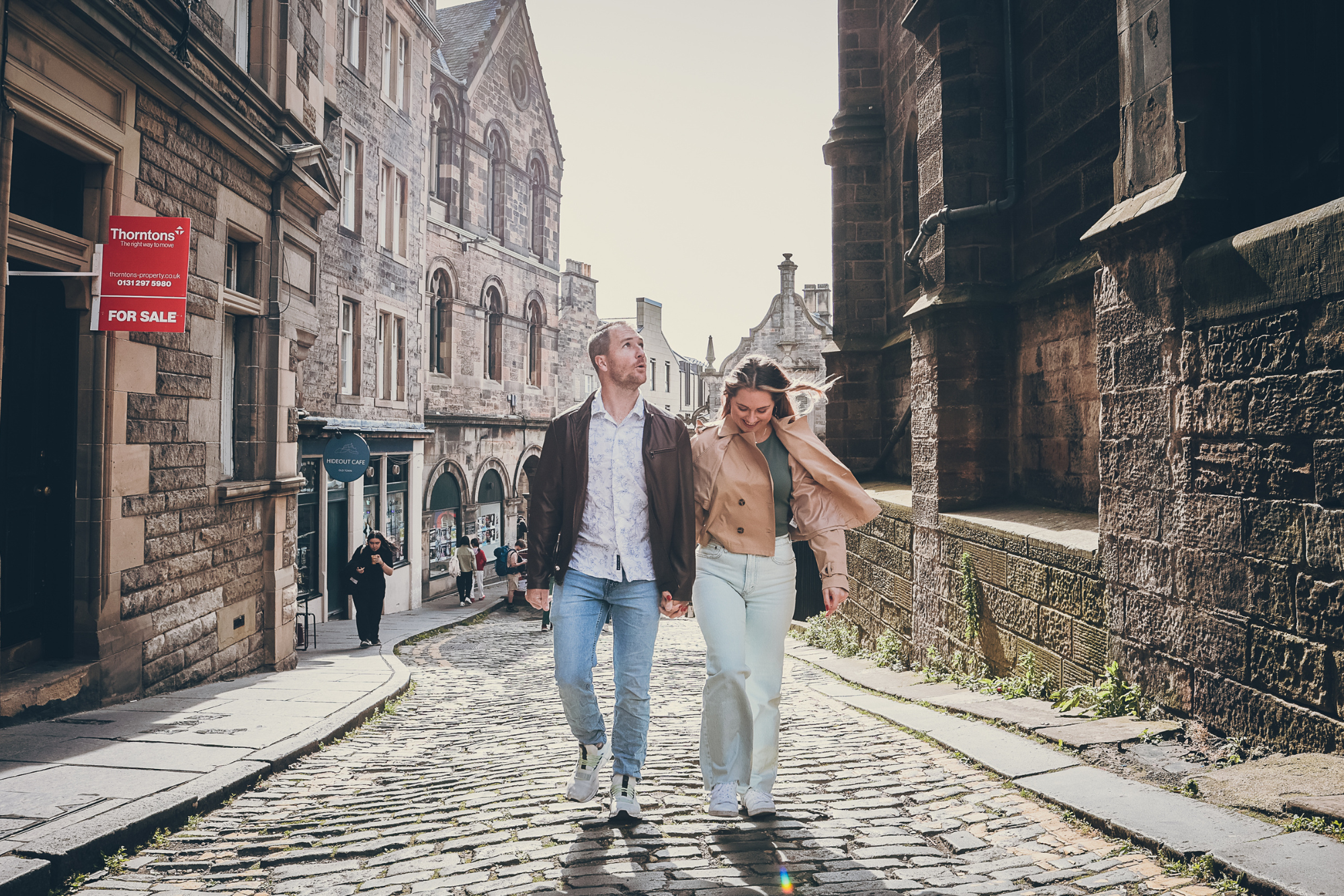 candid photo of a couple walking through the streets of edinburgh during a photoshoot