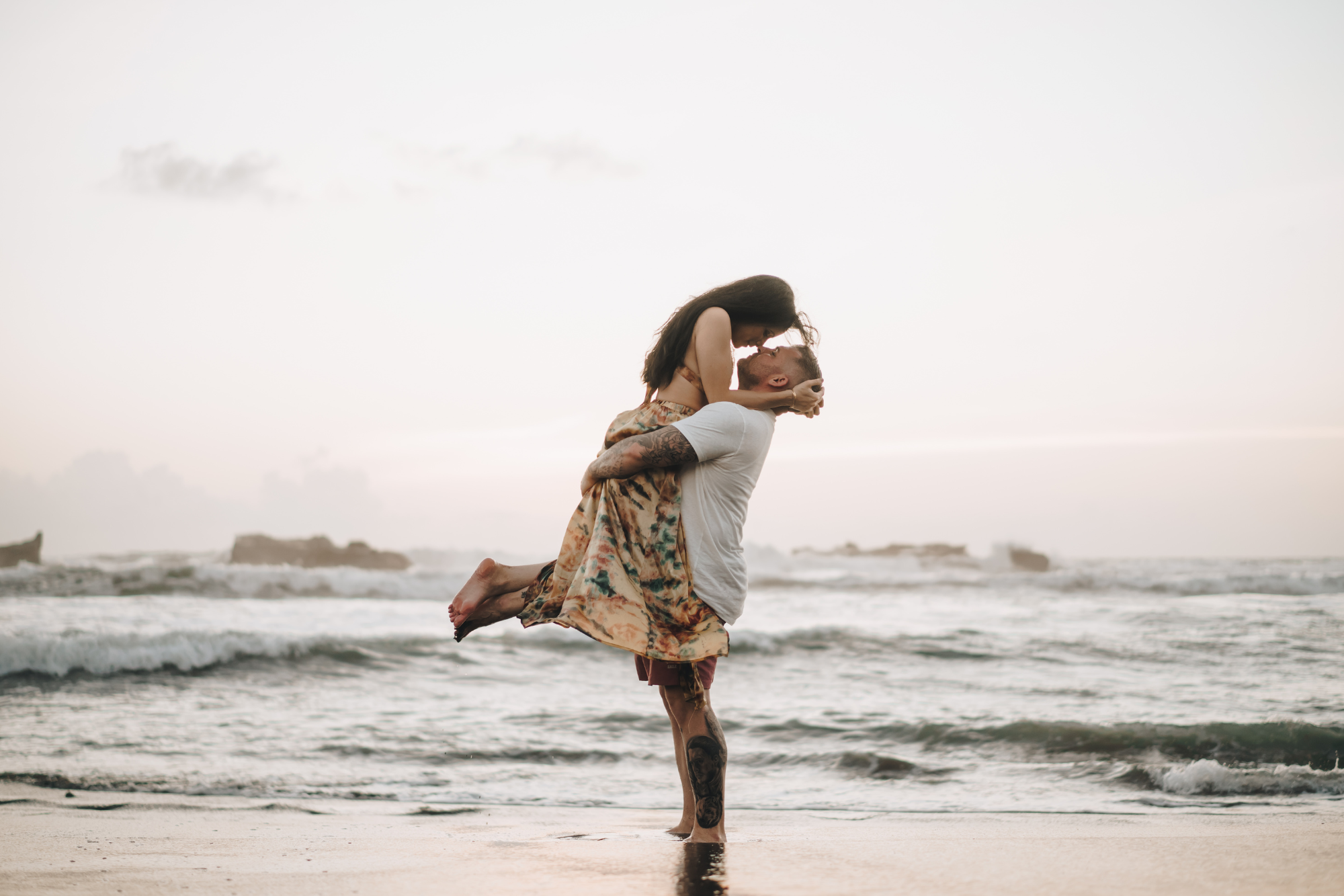 couple photoshoot in bali_ man holding a woman in his arms on the beach during golden hour