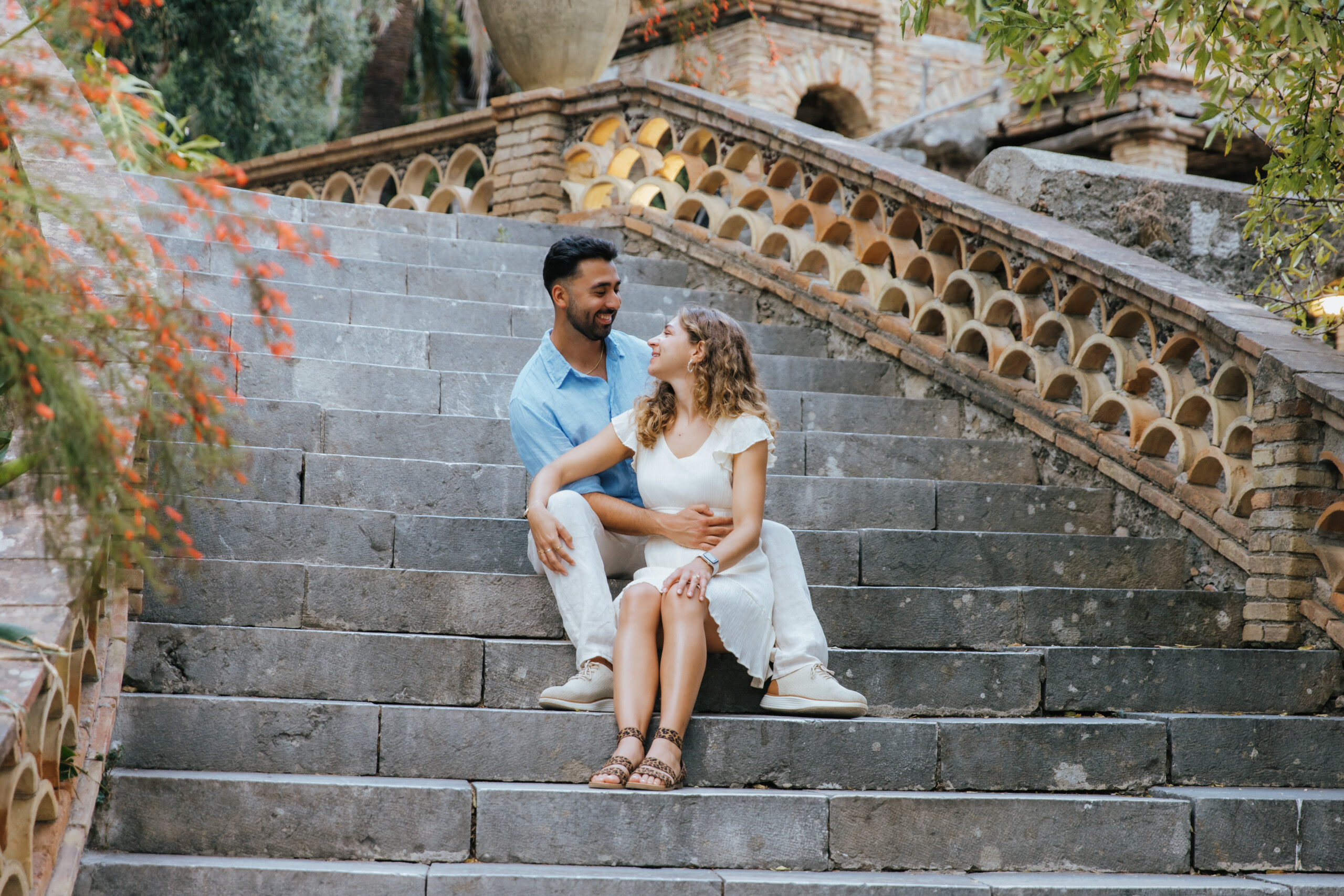 Couple looking at each other while sitting on stairs in Taormina