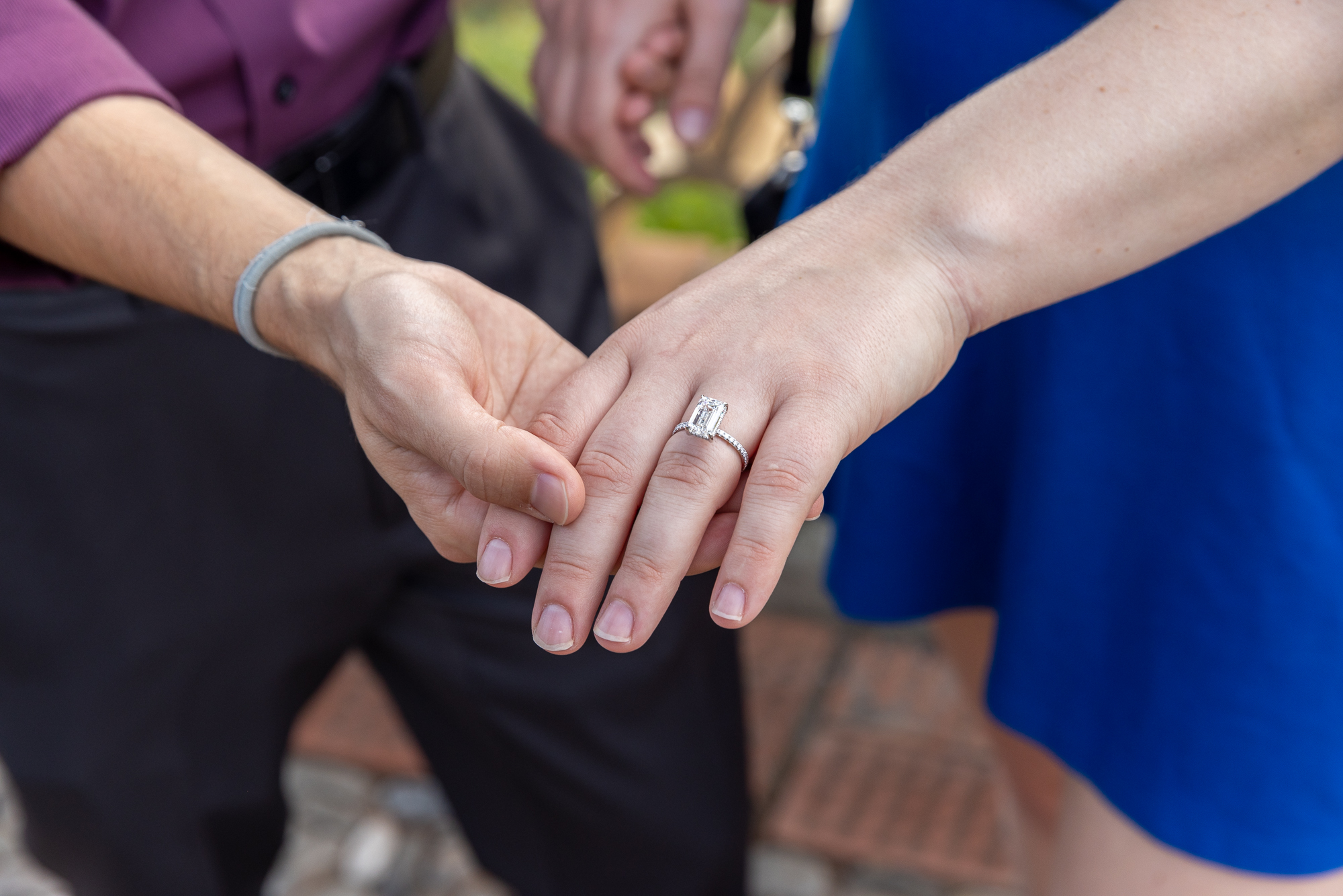 Man holding woman's hand with engagement ring