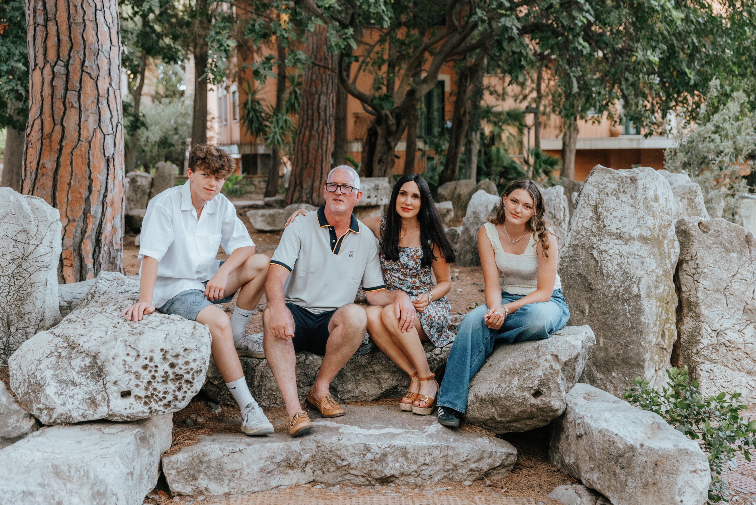 Family with children sitting on stones in Taormina