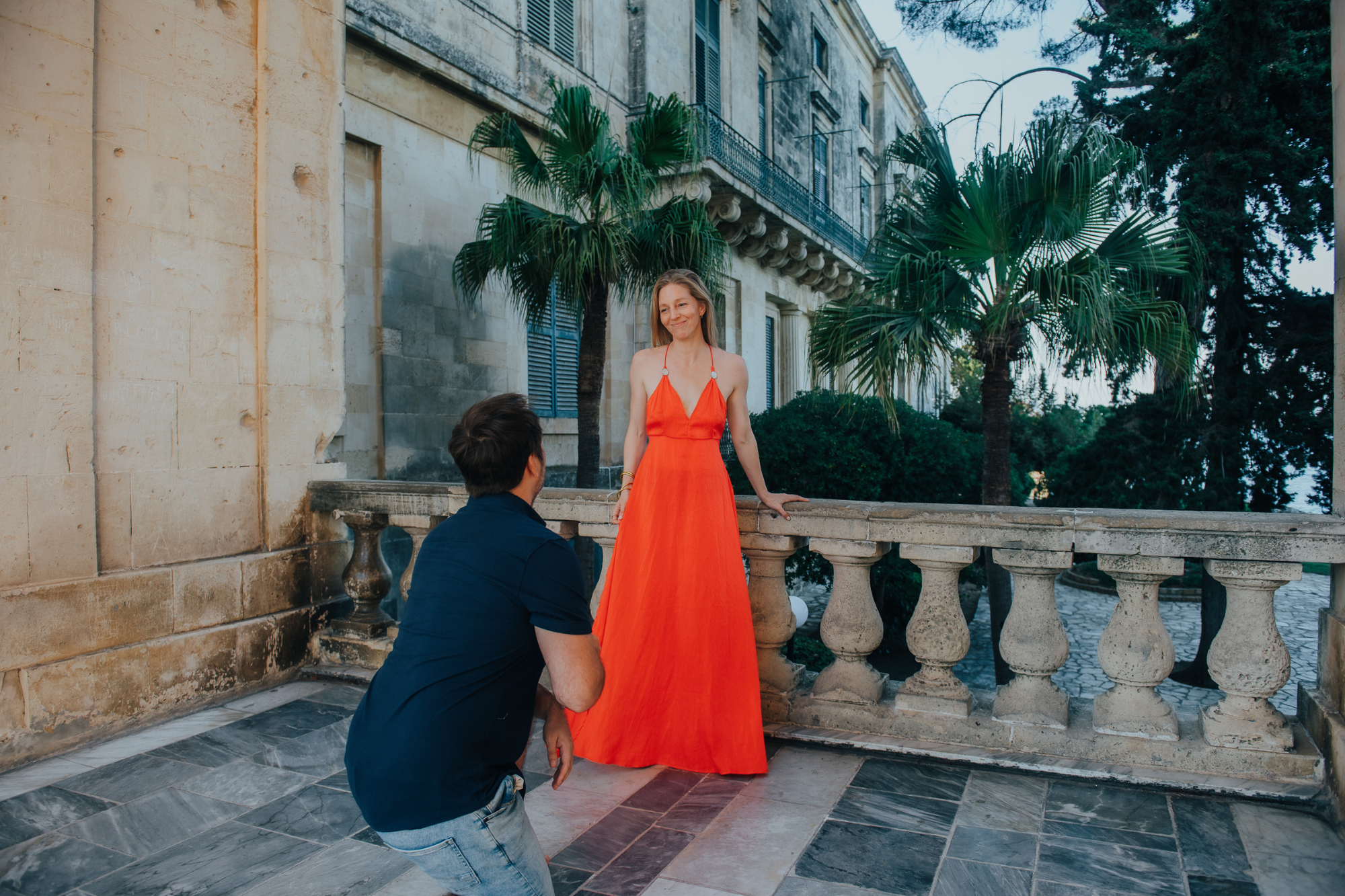 man proposing to his girlfriend in red dress in corfu