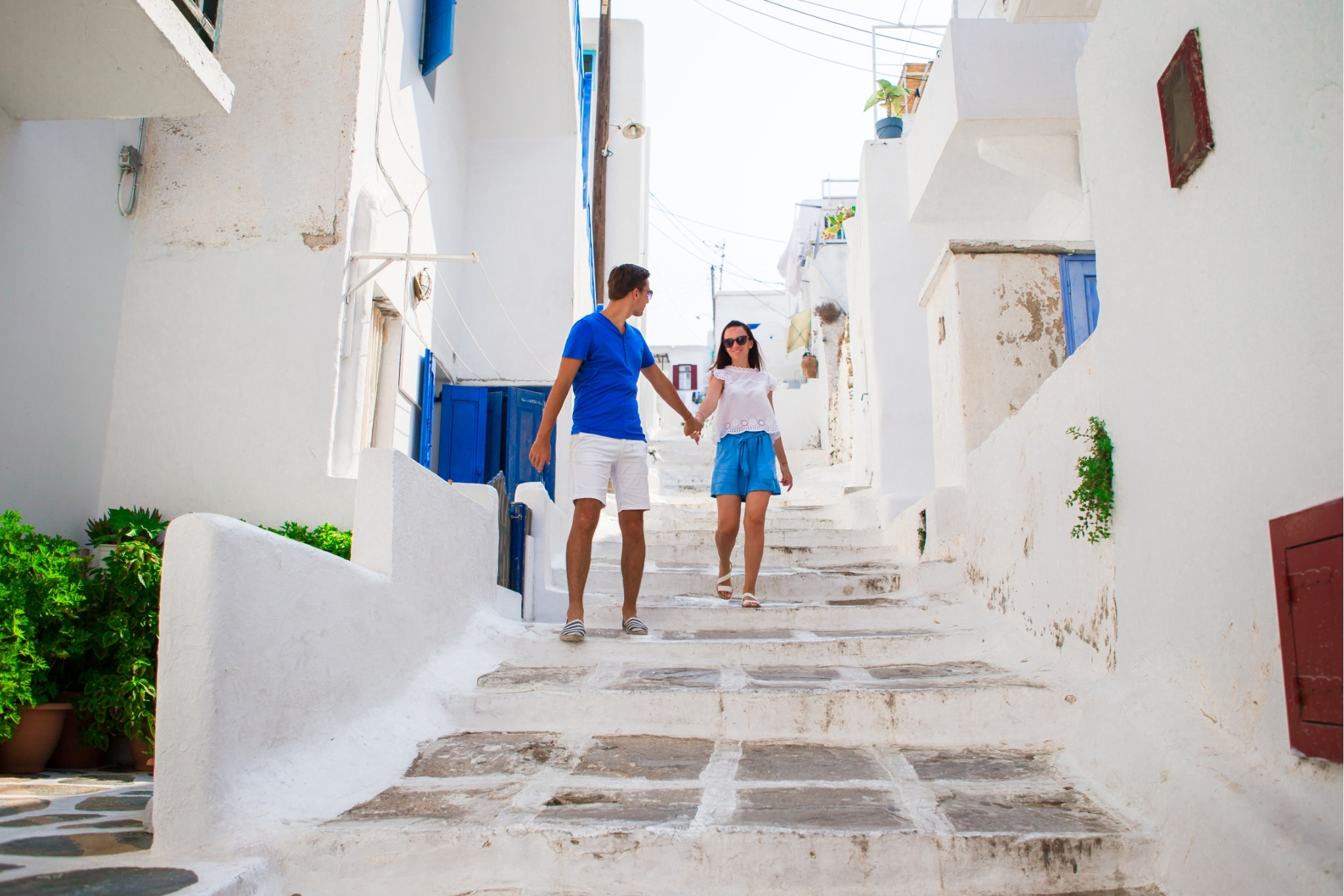 Couple dressed in white and blue walking through the streets in Mykonos