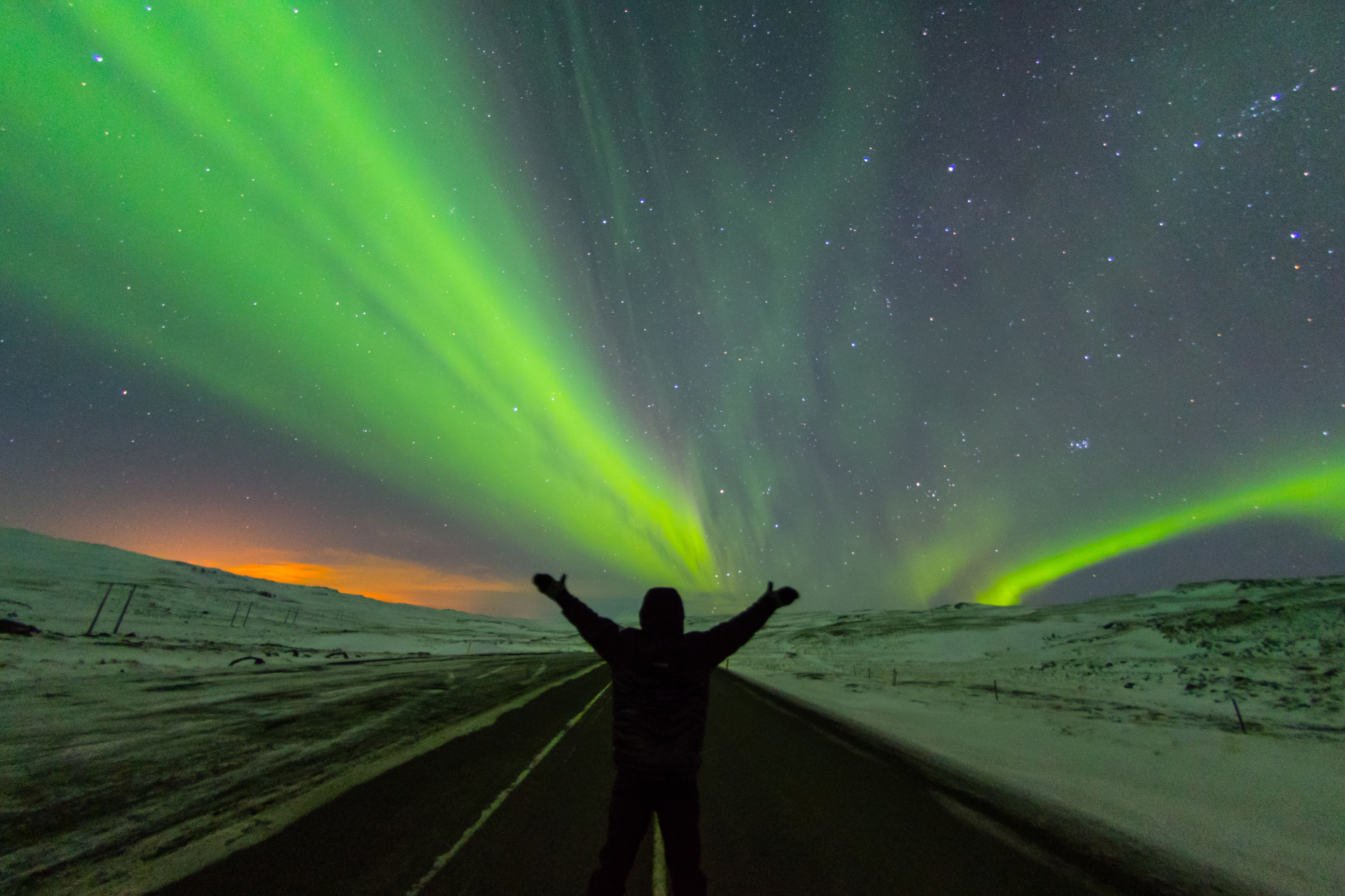 iceland aurora with man posing on the road